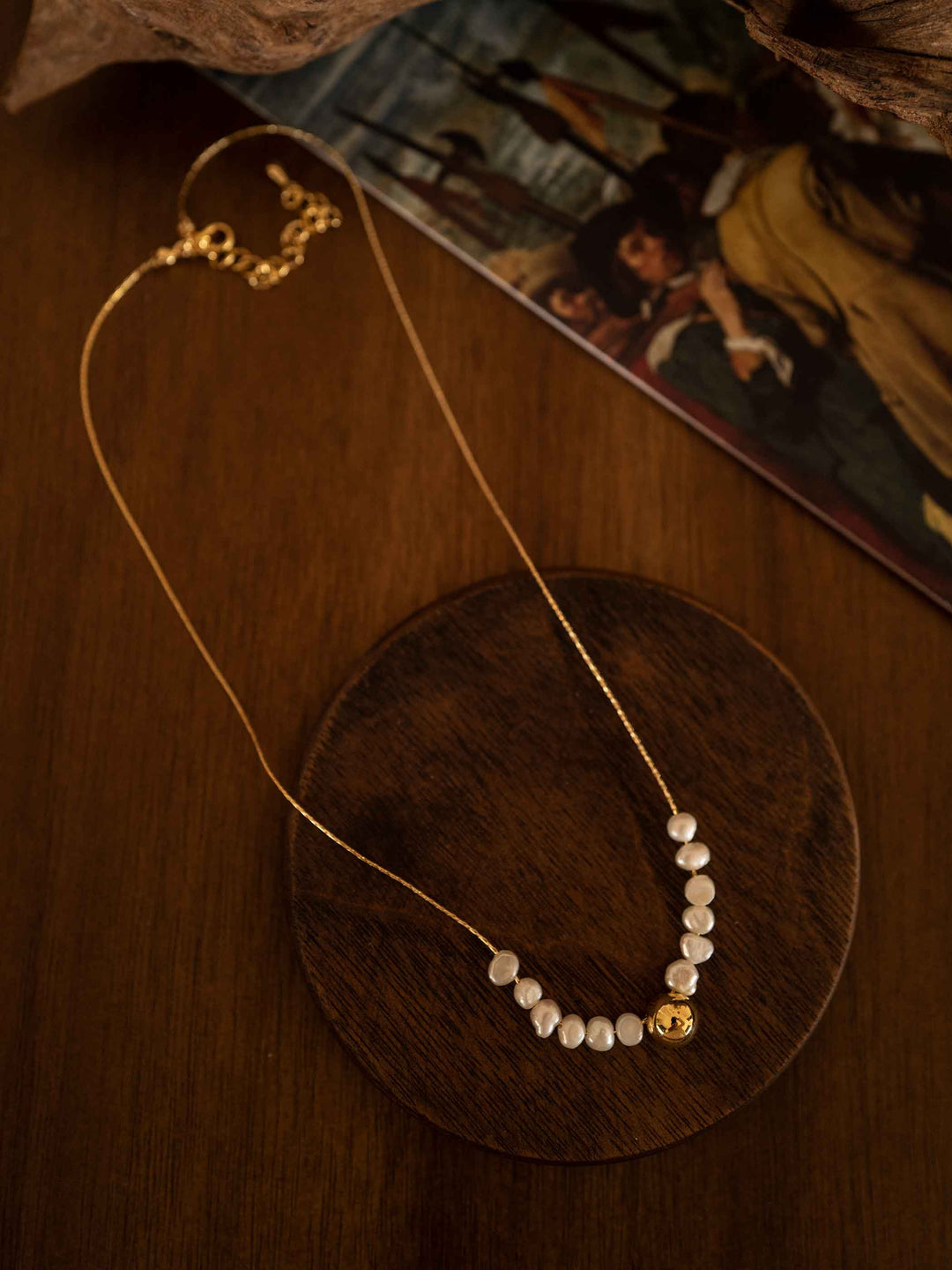 Collar de perlas de agua dulce en cuentas doradas bañadas en 18K sobre una bandeja de madera