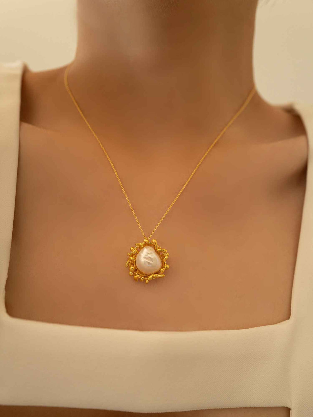 Una modelo luce un collar en forma de puesta de sol con perlas barrocas
